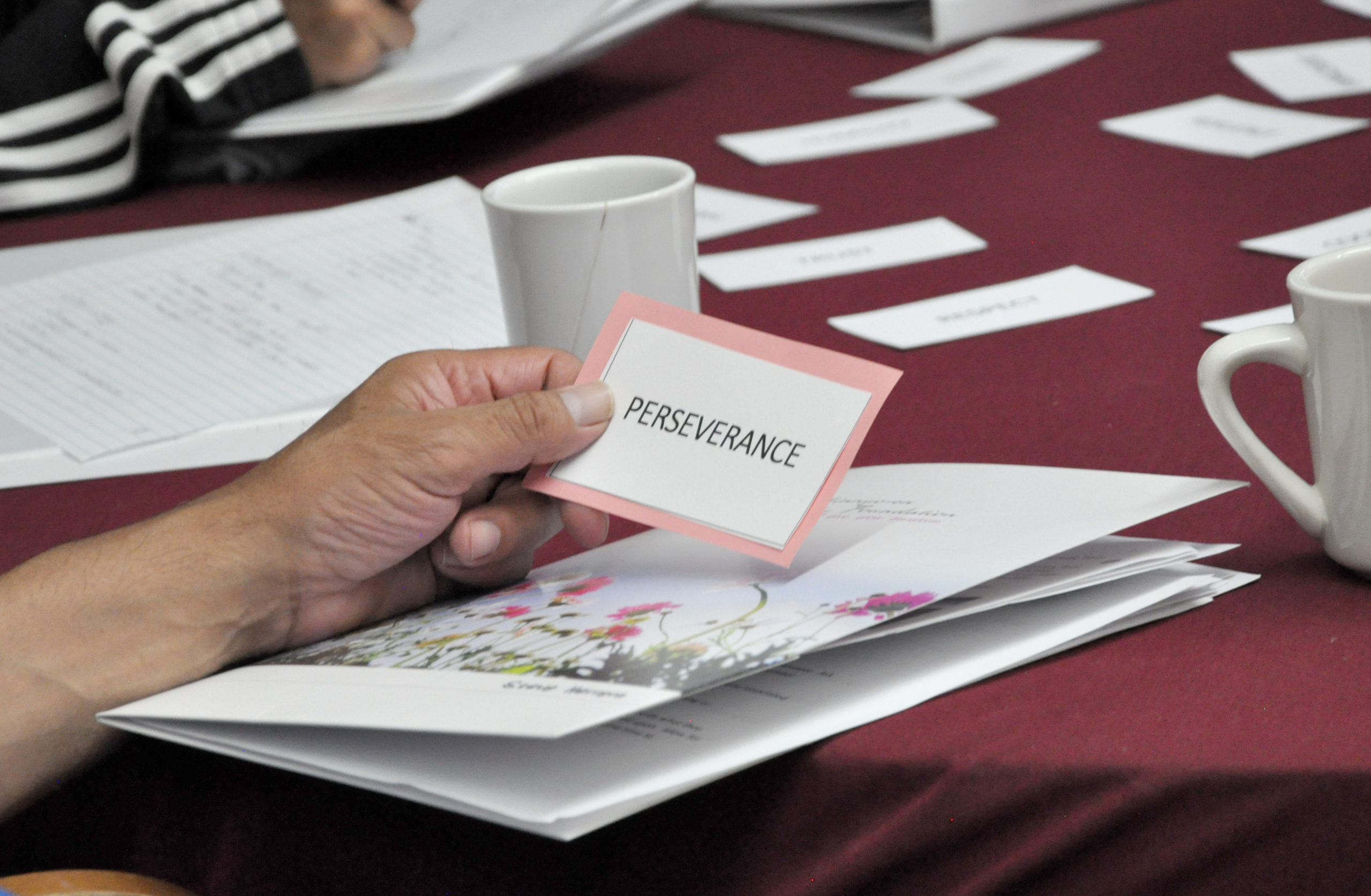 Hand holding a card that reads "Perseverance"